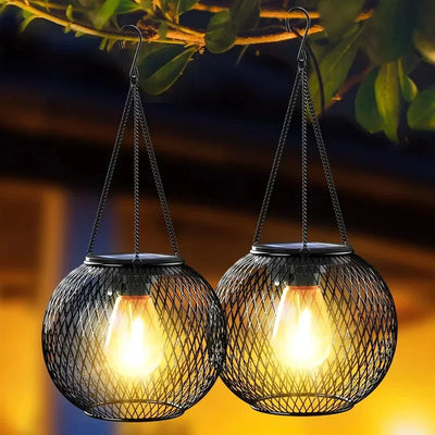 Two hanging solar lights with mesh covers on a blurred outdoor background